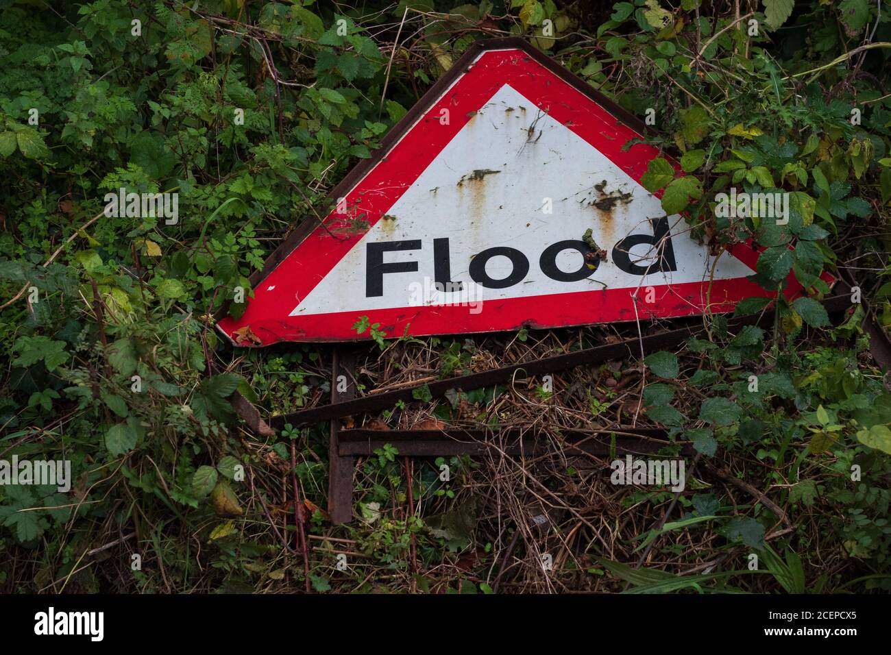 Warnschild für Hochwasser-Wettergefahr rostig und stürzte nach schweren Überschwemmungen an einem Straßenrand ein. England, Großbritannien. Stockfoto