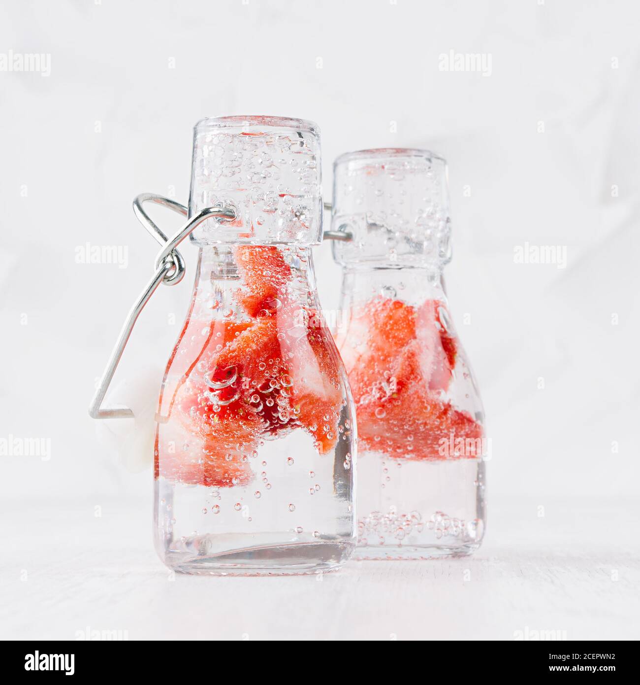 Kalte frische Fruchtgetränke von reifen Erdbeeren mit Sodawasser, Blasen auf einfachem weichen hellweißen Hintergrund, quadratisch. Stockfoto