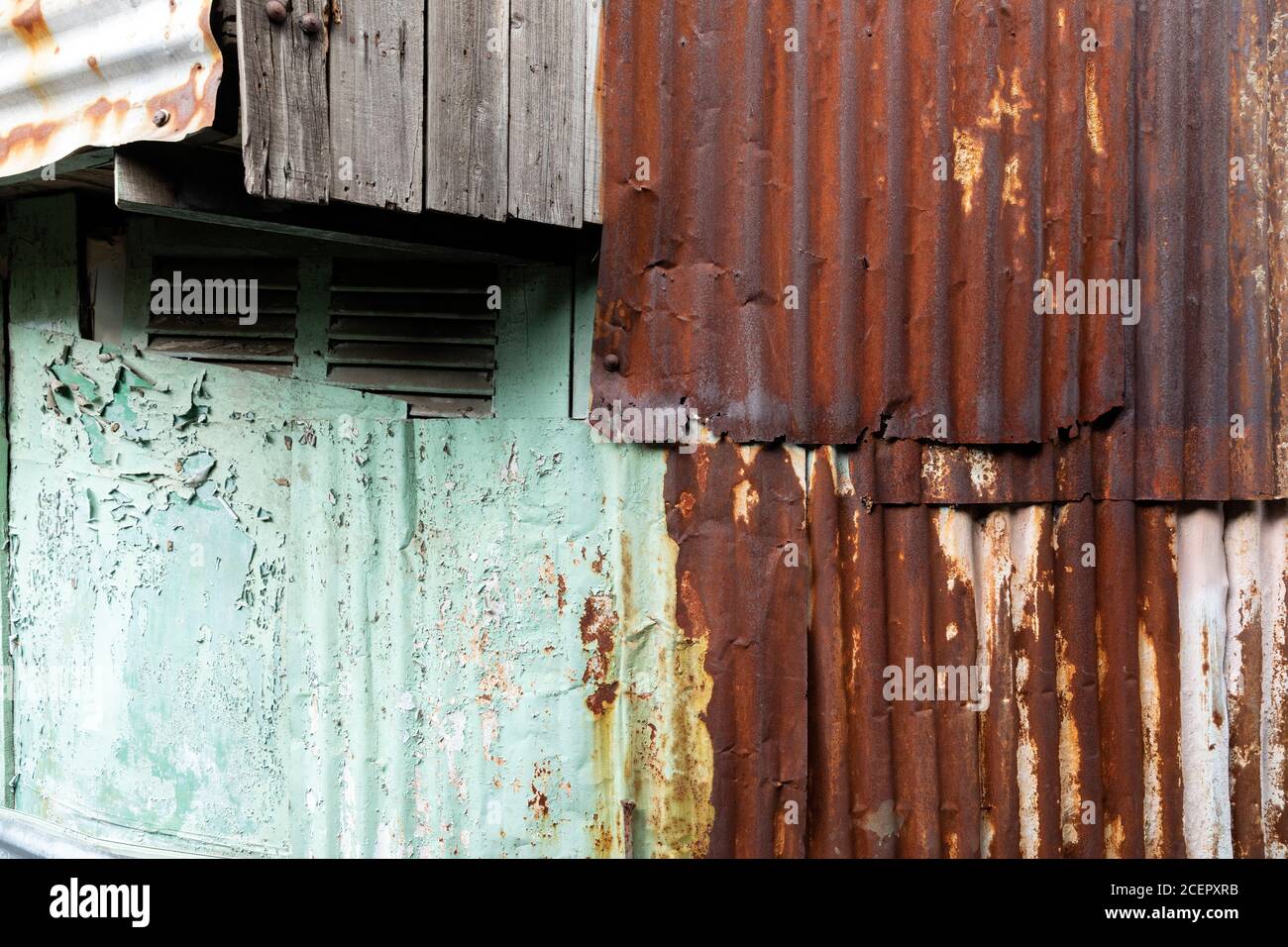 Texturen aus Wellblech, Holz, abblätternde Farbe auf einem alten Haus in einer armen Nachbarschaft Stockfoto