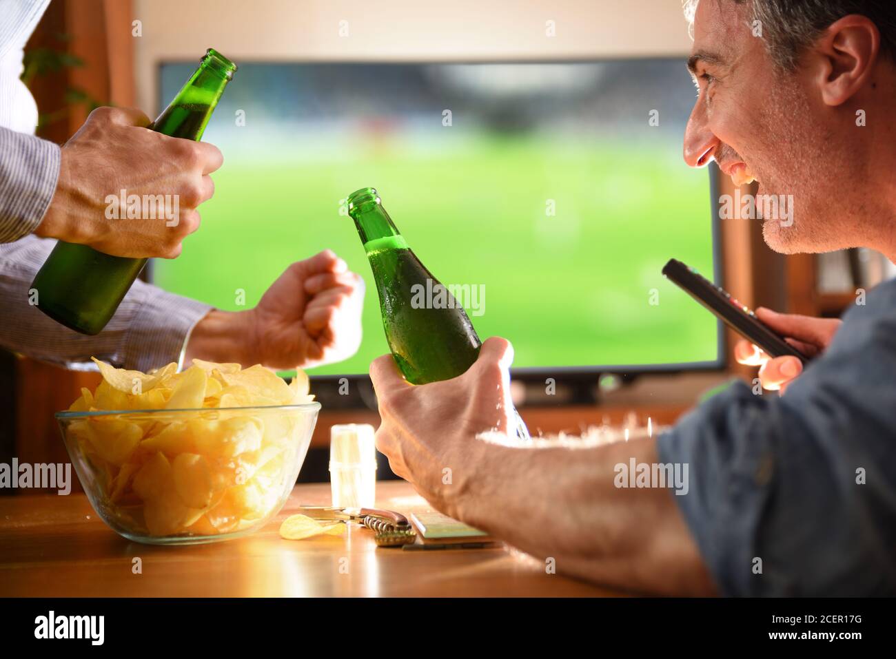 Mann zu Hause mit Freunden beobachten Spiel im Fernsehen mit Bier und Chips Stockfoto
