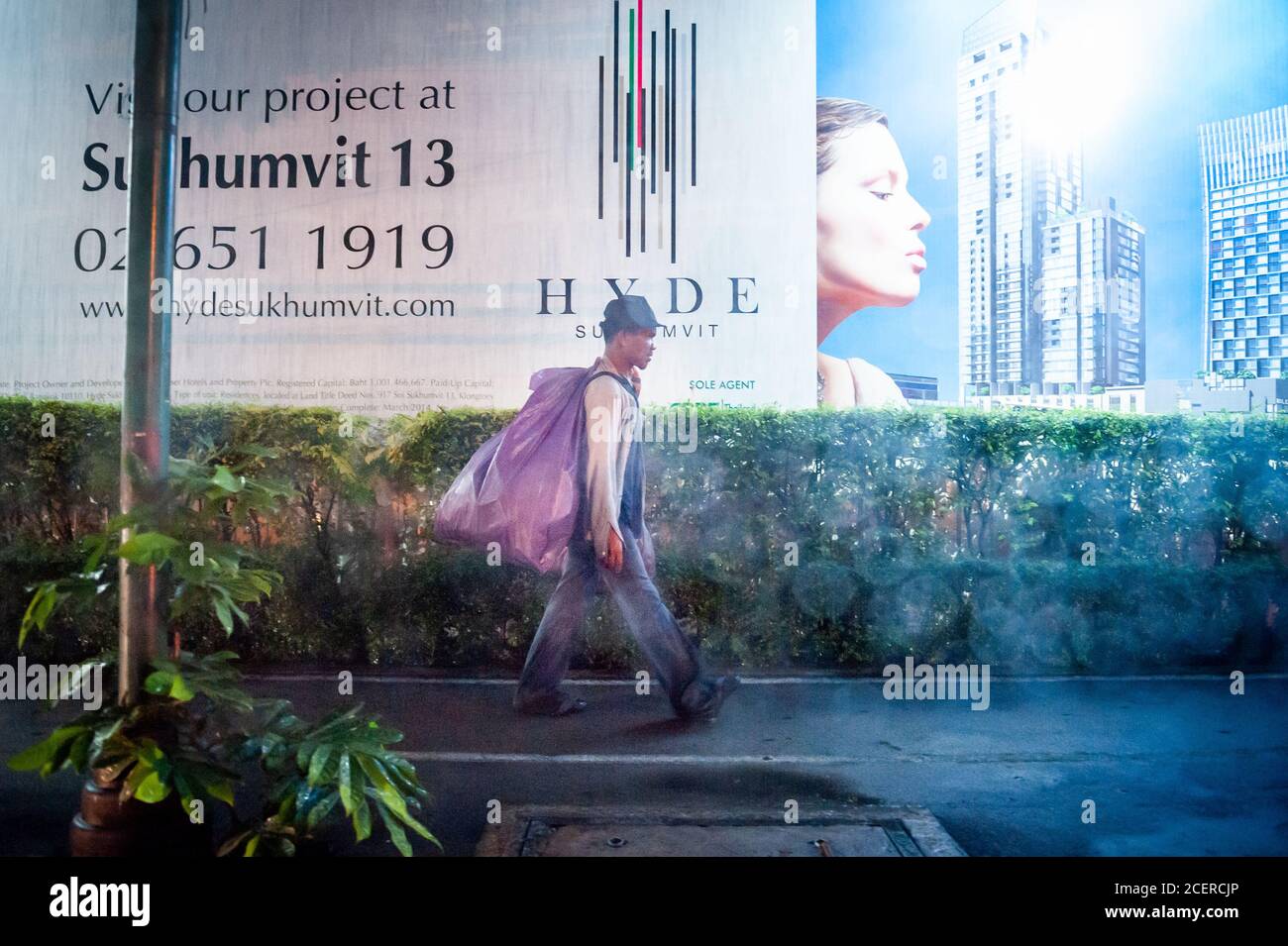 Ein Thailänder macht sich auf den Weg an einer Baustelle entlang der durchnässten Sukhumvit Rd. Bangkok, Thailand. Stockfoto