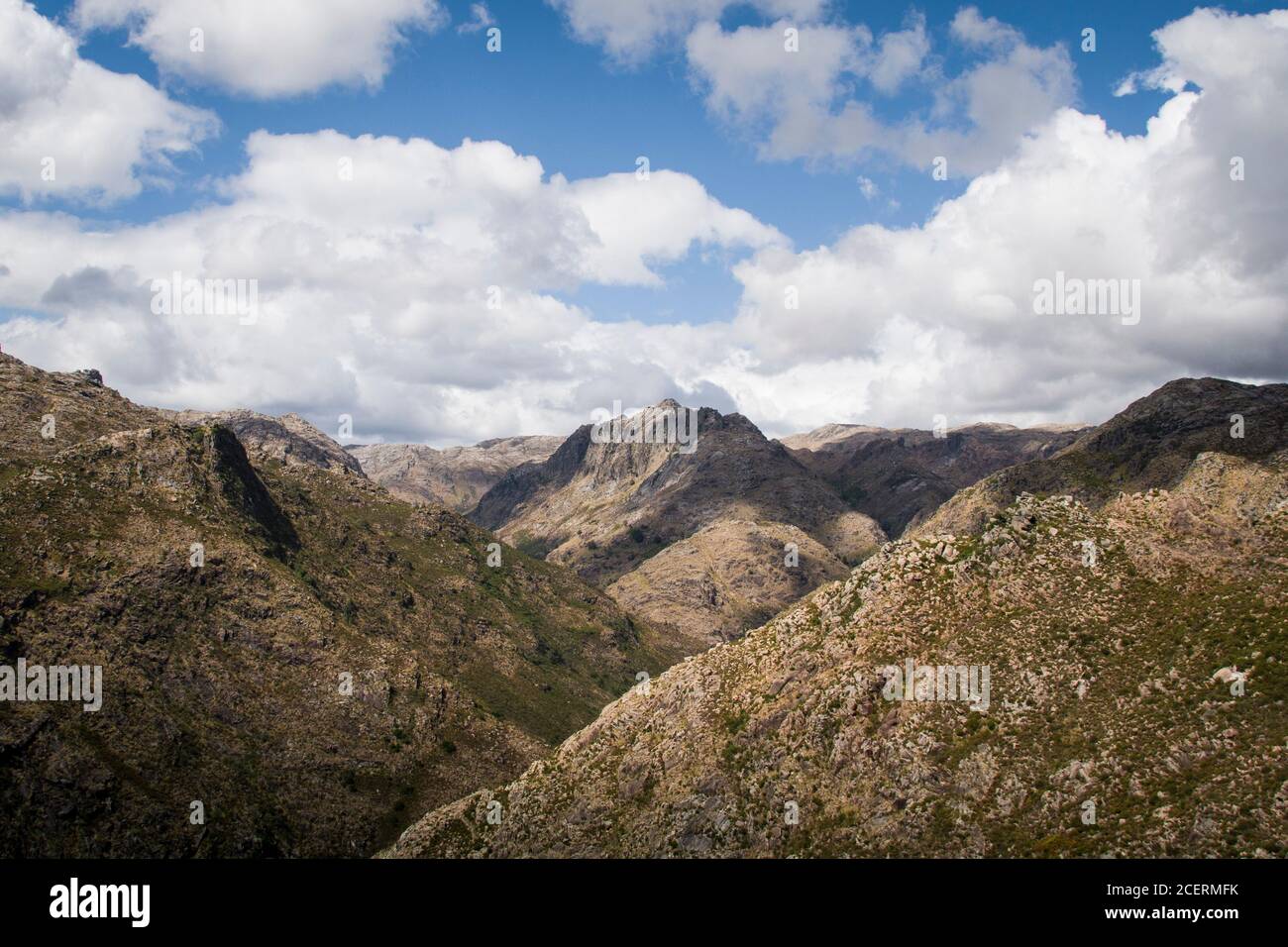 Die Wolken, die am Himmel vorbeiziehen, geben Schatten und Kontrast Zu einer breiten Berglandschaft darunter Stockfoto