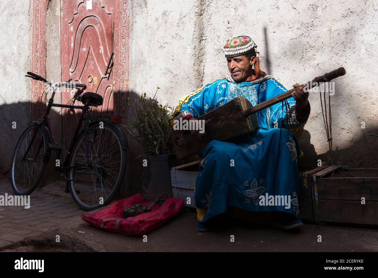 Musiker, der auf einem Gimbi (alias sintir) auf einer Straße in der Medina, Marrakesch, mit Gnawa-Musik unterwegs ist. Stockfoto