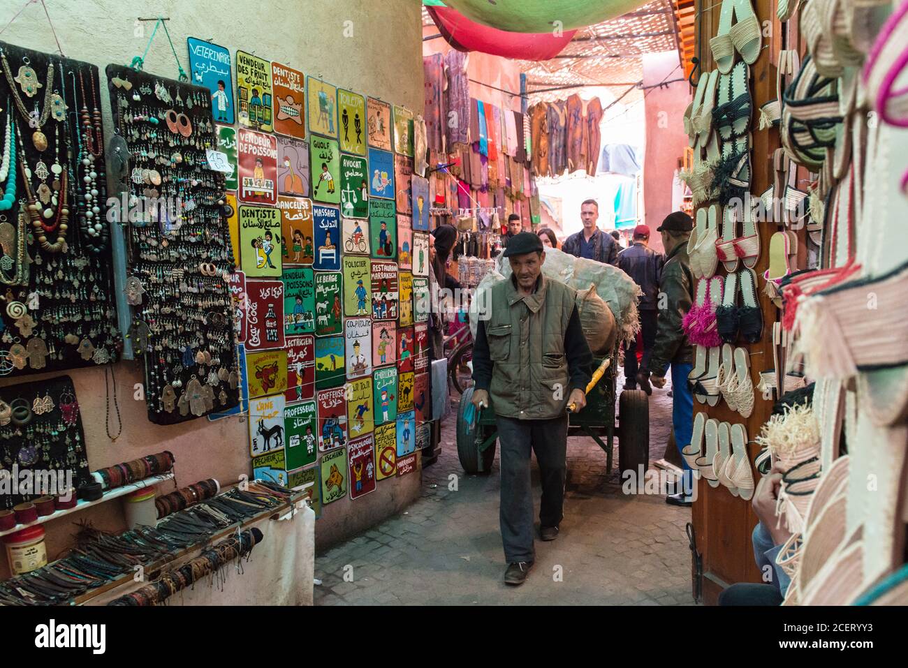 Marktportier zieht Hand gezogenen Wagen vorbei Marktstände im Souk innerhalb der Medina, Marrakesch Stockfoto