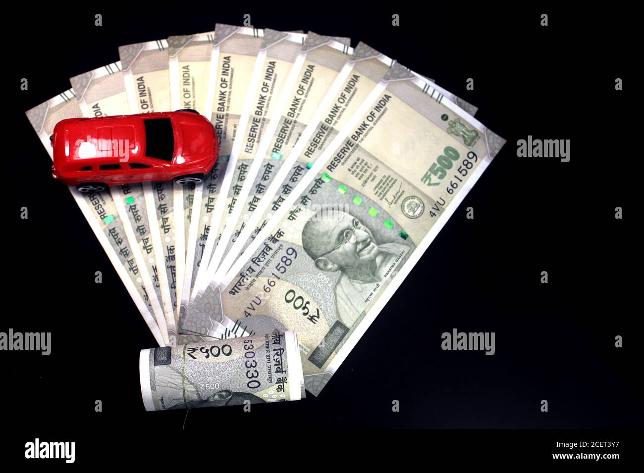 Indische Währung. 500 Rupie-Note mit Spielzeugauto. Indische Währung auf schwarzem Hintergrund isoliert. Kauf Auto Konzept. Stockfoto