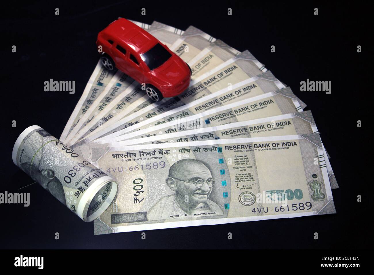 Indische Währung. 500 Rupie-Note mit Spielzeugauto. Indische Währung auf schwarzem Hintergrund isoliert. Kauf Auto Konzept. Stockfoto