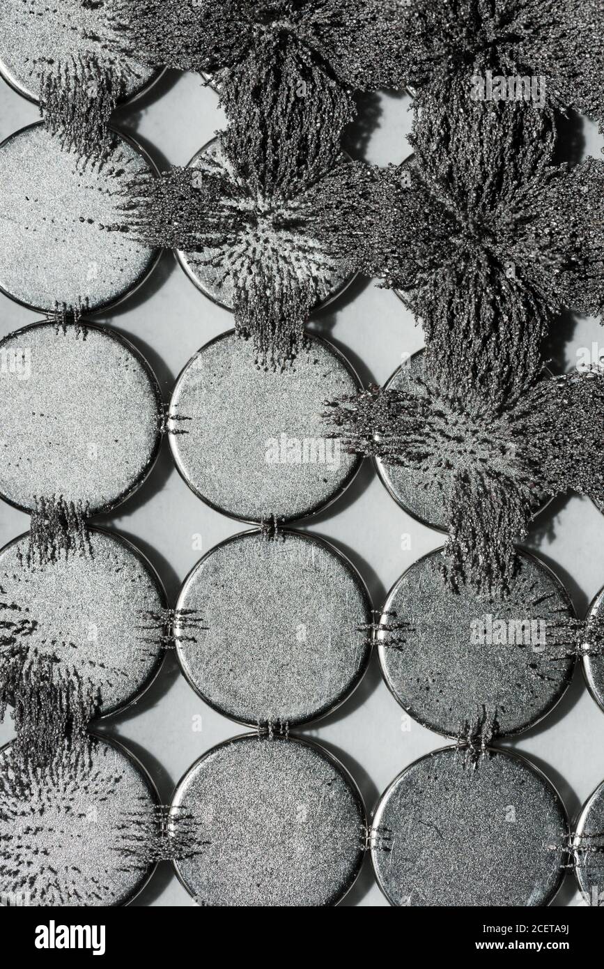 Unsichtbare magnetische Fluss sichtbar gemacht mit Eisen Späne schaffen interessant Ineinandergreifende Muster mit kreisförmigem Magneten Stockfoto Unsichtbare magnetische Fluss sichtbar gemacht mit Eisen Späne schaffen interessant Ineinandergreifende Muster mit kreisförmigem Magneten Stockfoto