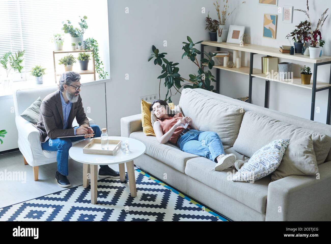 Junge Frau mit Depressionen auf dem Sofa liegend ihre Probleme mit Psychologen teilen, High-Angle-View-Aufnahme Stockfoto