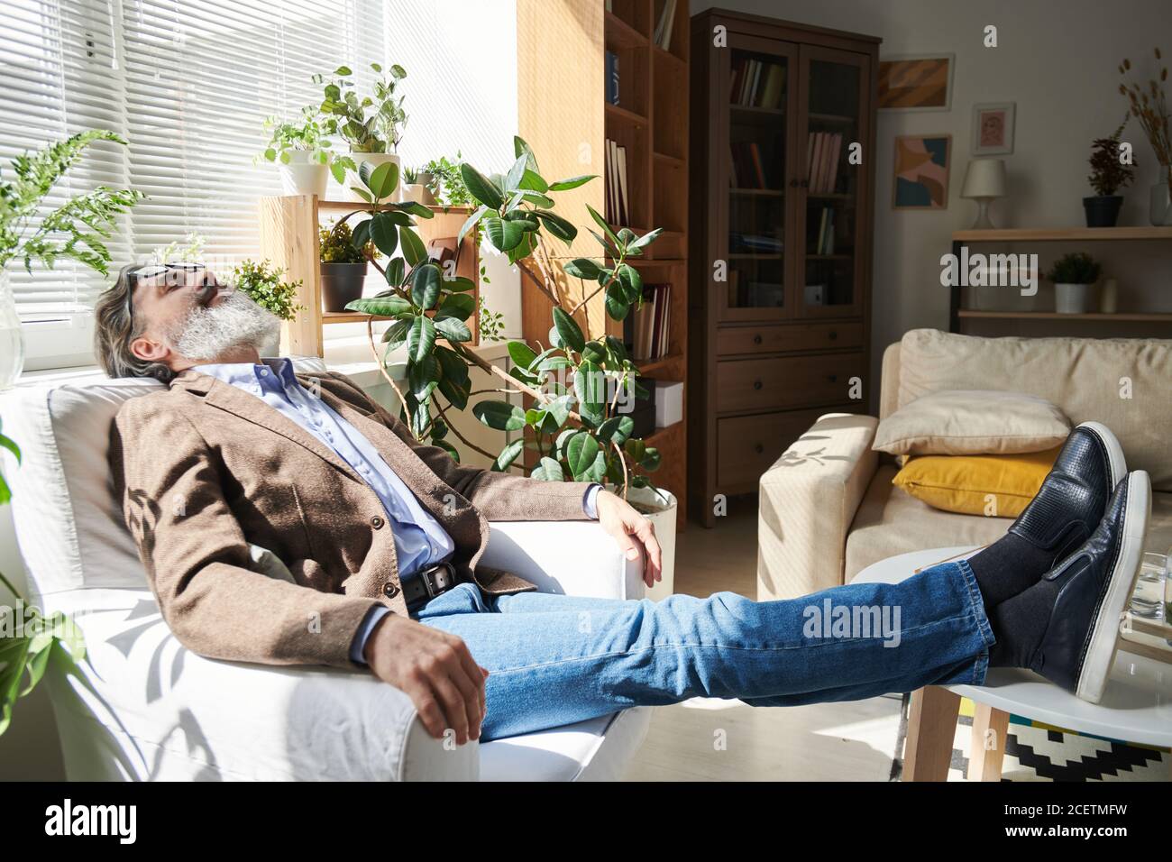 Müder Psychologe, der in der Pause nach der Therapie ein Nickerchen im Sessel macht, Ganzkörperaufnahme, Kopierraum Stockfoto