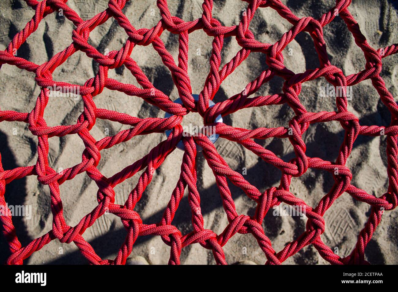 Textur eines Sitzes aus Seilen. Rote geflochtene Seile, die in der Mitte von einem Metallring gehalten werden. Stockfoto
