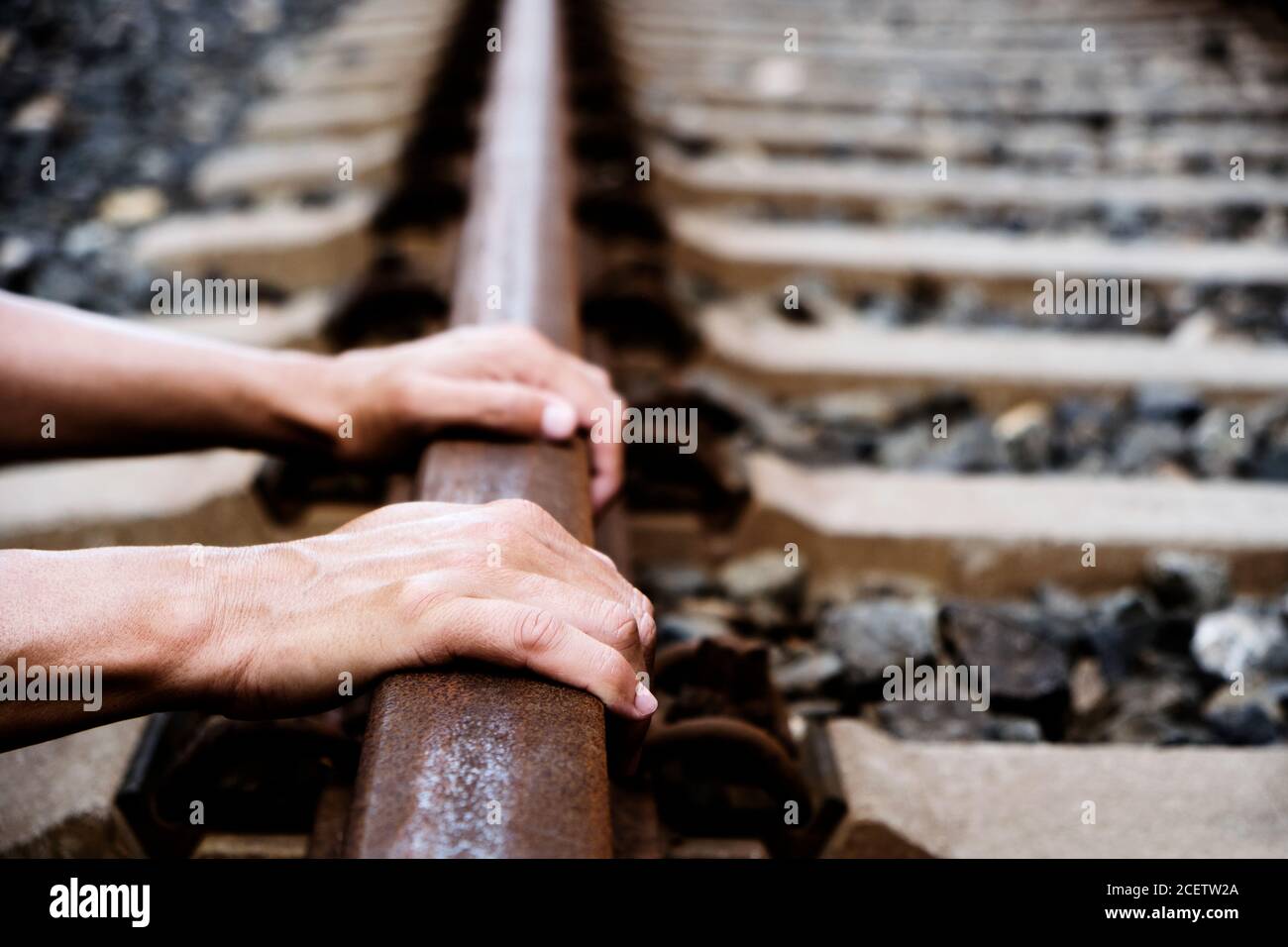 Nahaufnahme der Hände eines kaukasischen Mannes auf dem Eisenbahnschienen Stockfoto