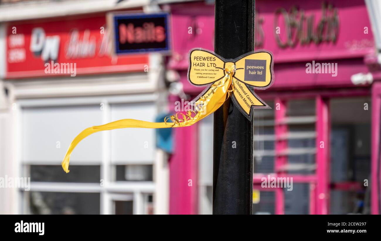 Ein goldenes Band wird in der Mitte einer Fußgängerzone zur Erinnerung an den Kinderkrebs Sensibilisierungsmonat angezeigt. Stockfoto