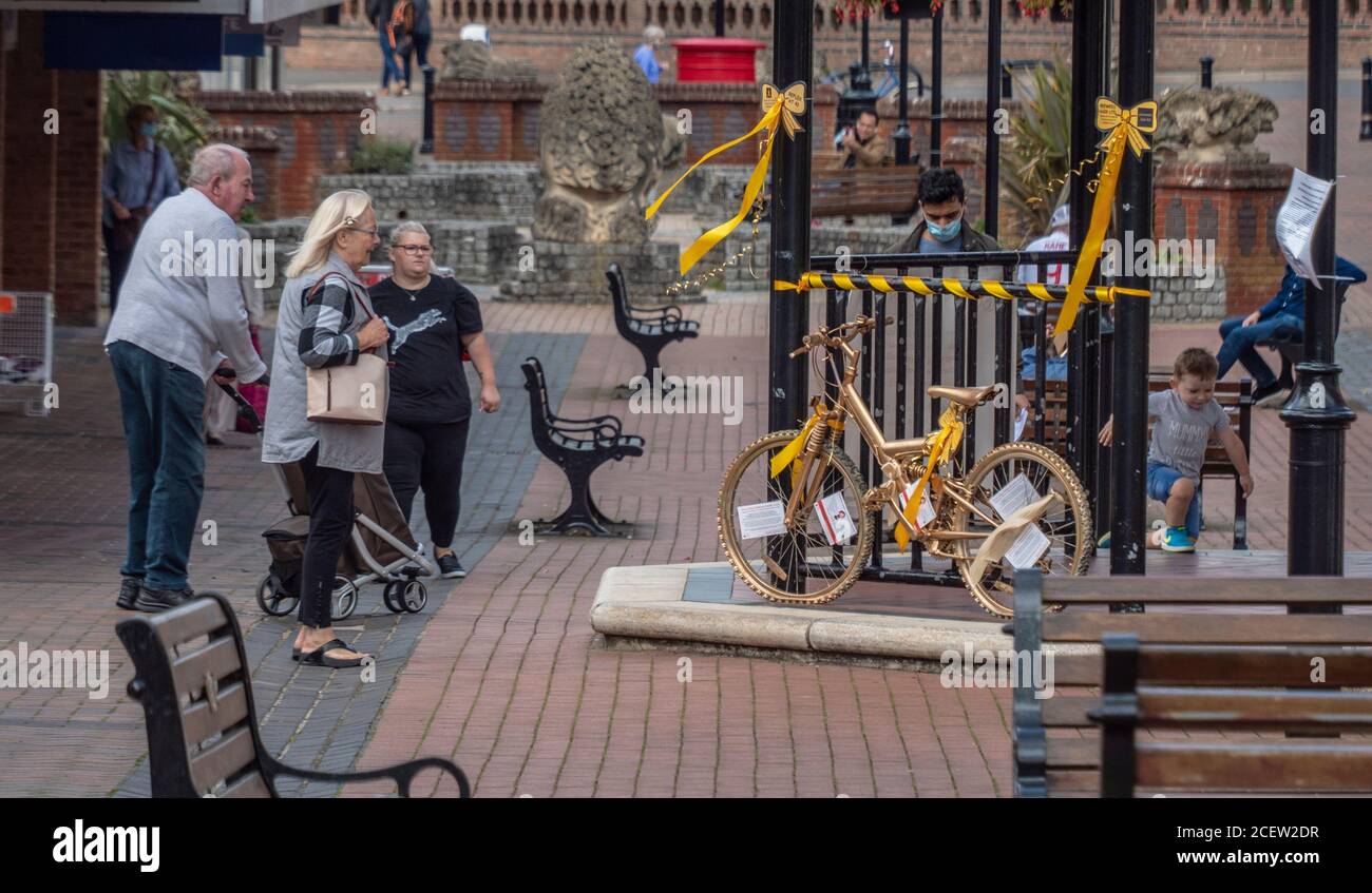 Ein Fahrrad mit Gold gesprüht wird in der Mitte einer Fußgängerzone zur Erinnerung an die Kindheit Krebs Bewusstsein Monat angezeigt. Stockfoto