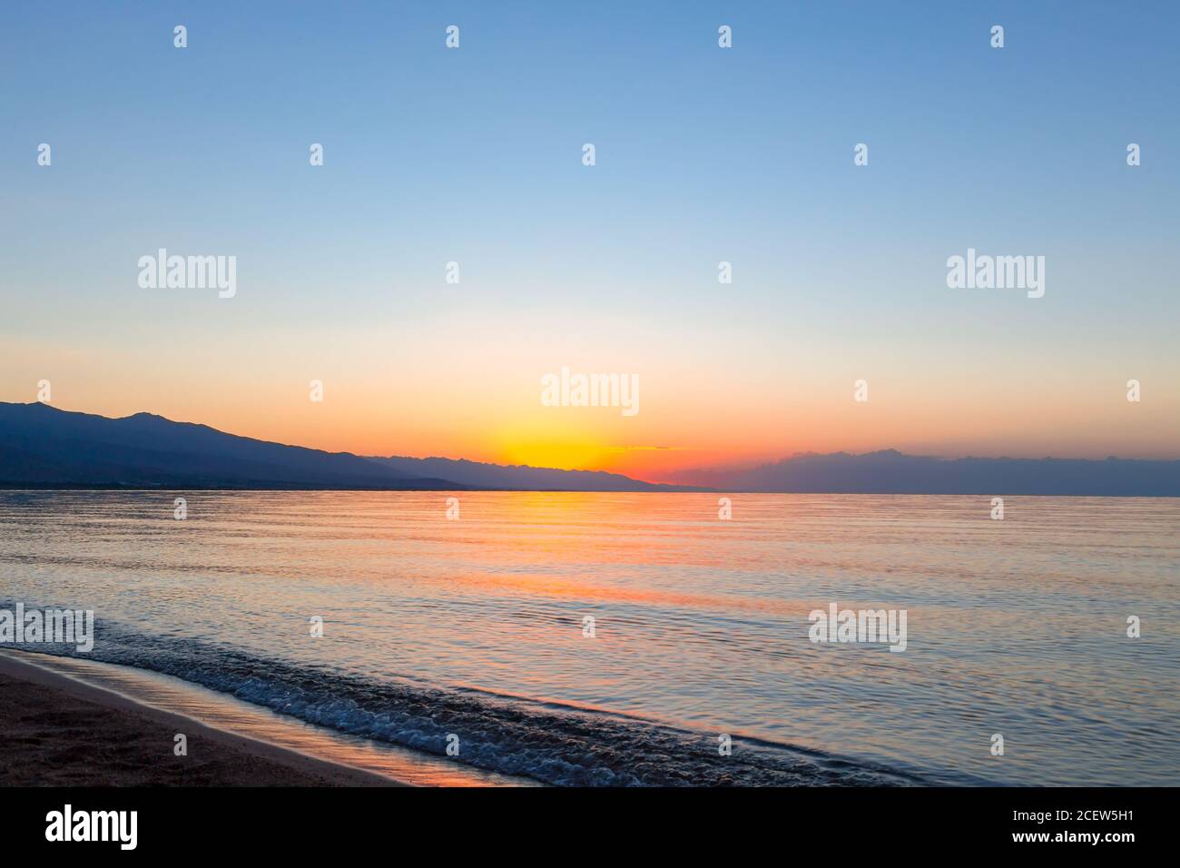 Sonnenaufgang auf dem Meer. Die aufgehende Sonne hinter den Bergen. Kirgisistan. Stockfoto
