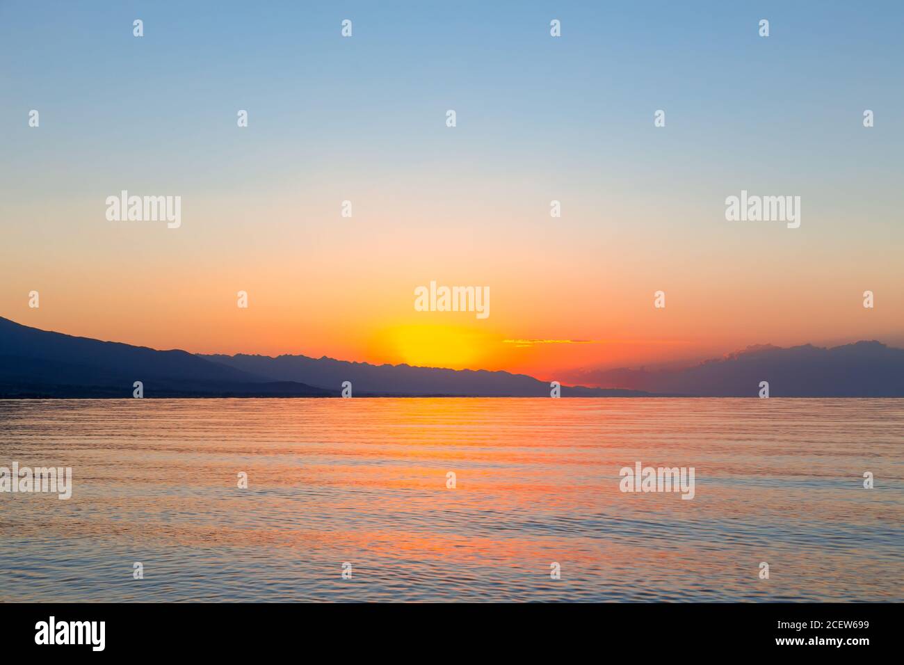 Sonnenaufgang auf dem Meer. Die aufgehende Sonne hinter den Bergen. Kirgisistan. Stockfoto