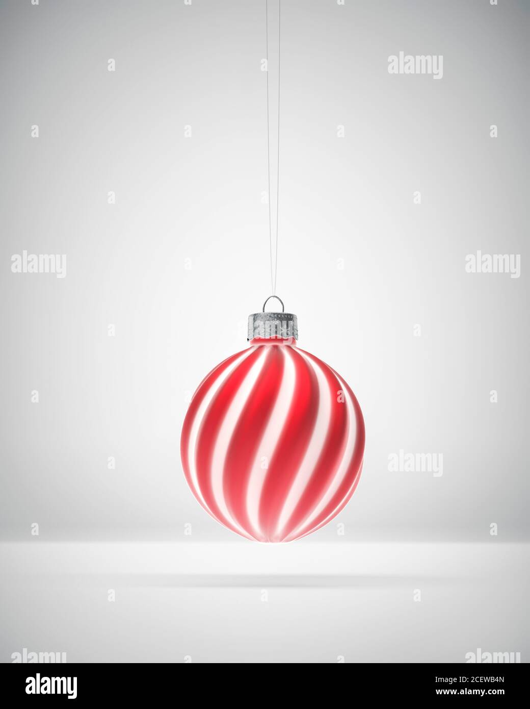 Matt rot und weiß gestreiften Weihnachtsschmuck hängen vor weißem Hintergrund. Diffuses Licht. Weihnachtsdekoration, festliches Atmosphärenkonzept. Stockfoto