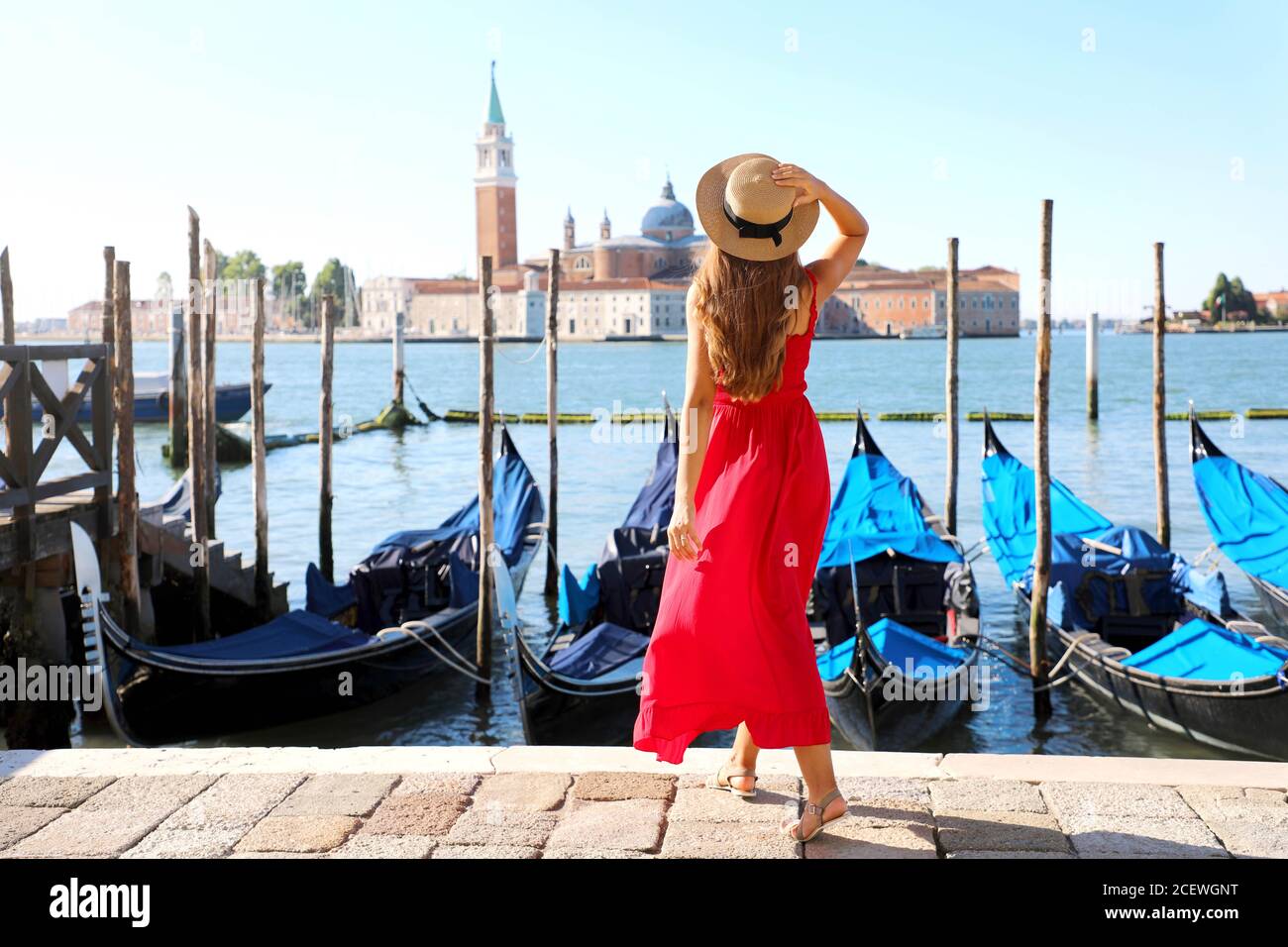Rückansicht der schönen Mädchen in roten Kleid zu Fuß in Venedig mit Gondeln vor Anker Stockfoto