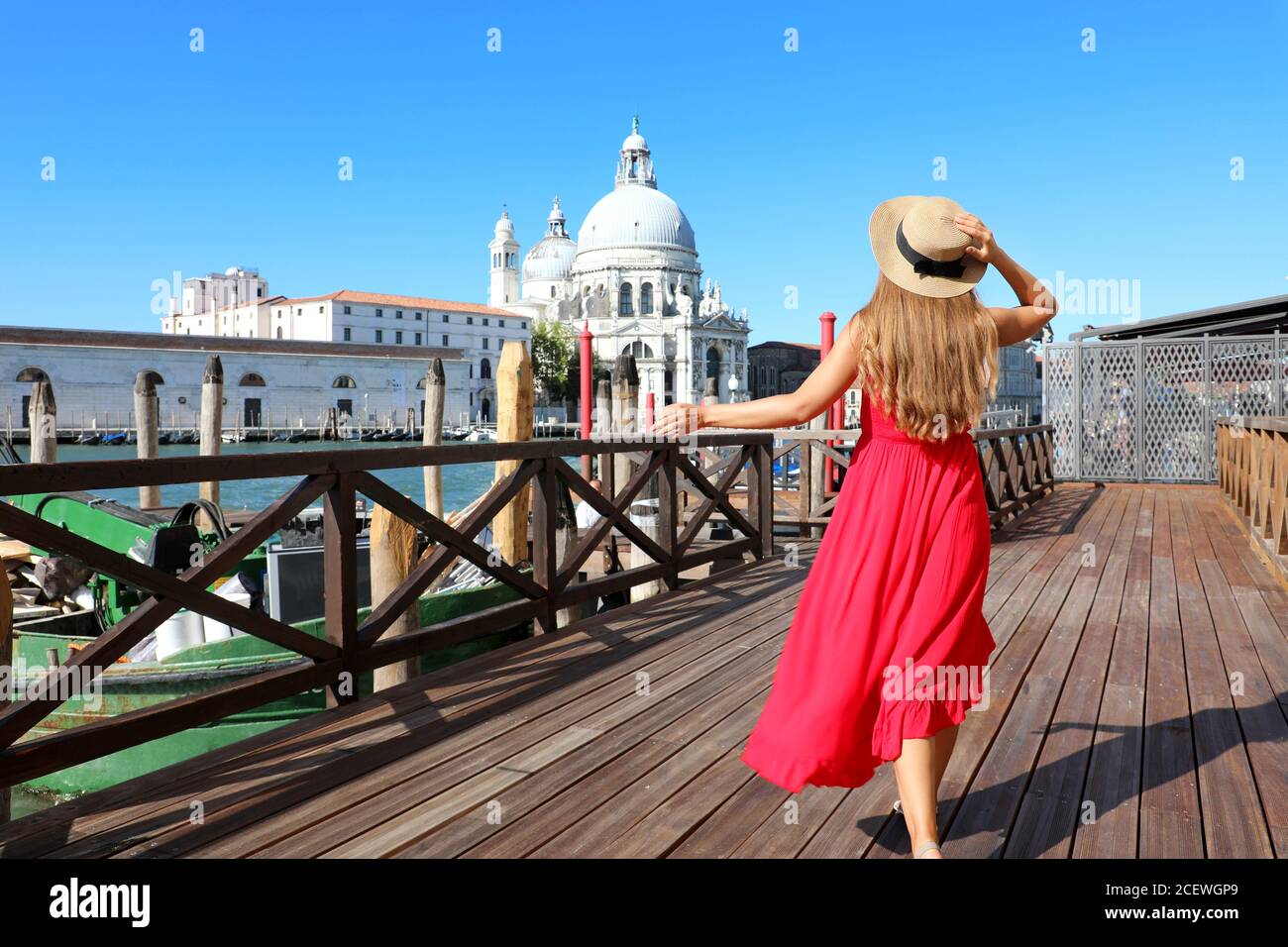 Junge Frau mit rotem Kleid und Hut geht in Venedig, Italien Stockfoto
