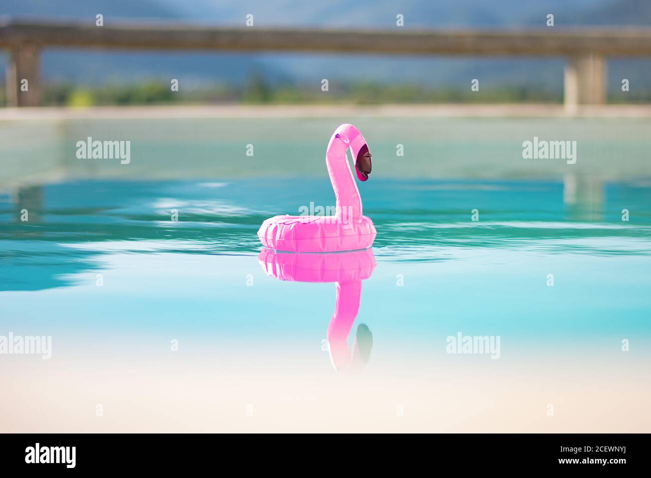 Aufblasbare Flamingo Spielzeug sanft schwebt über Schwimmbad mit landschaftlich Berghintergrund Stockfoto