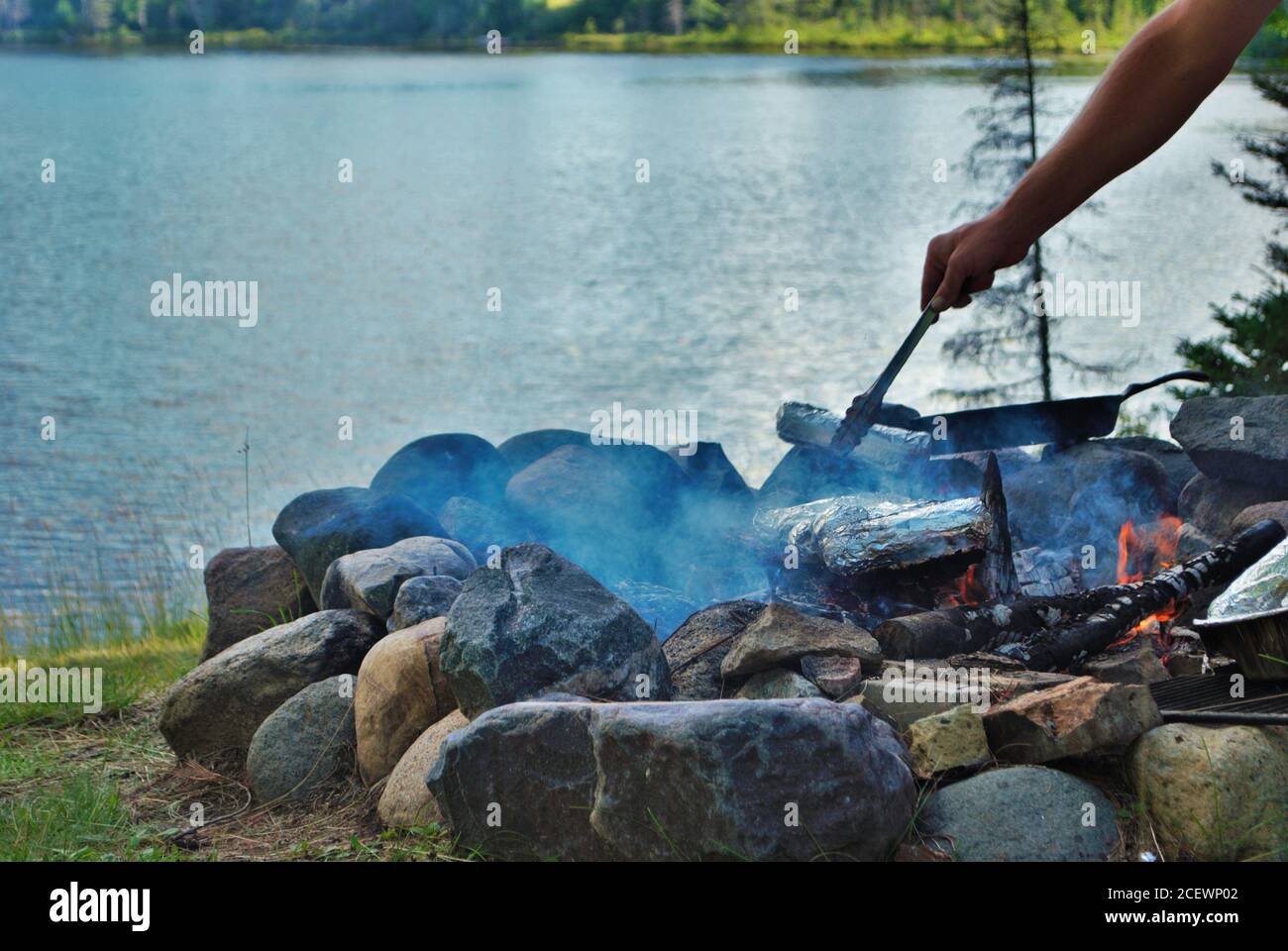 Kochen von Mais auf einem Lagerfeuer neben dem See Stockfoto