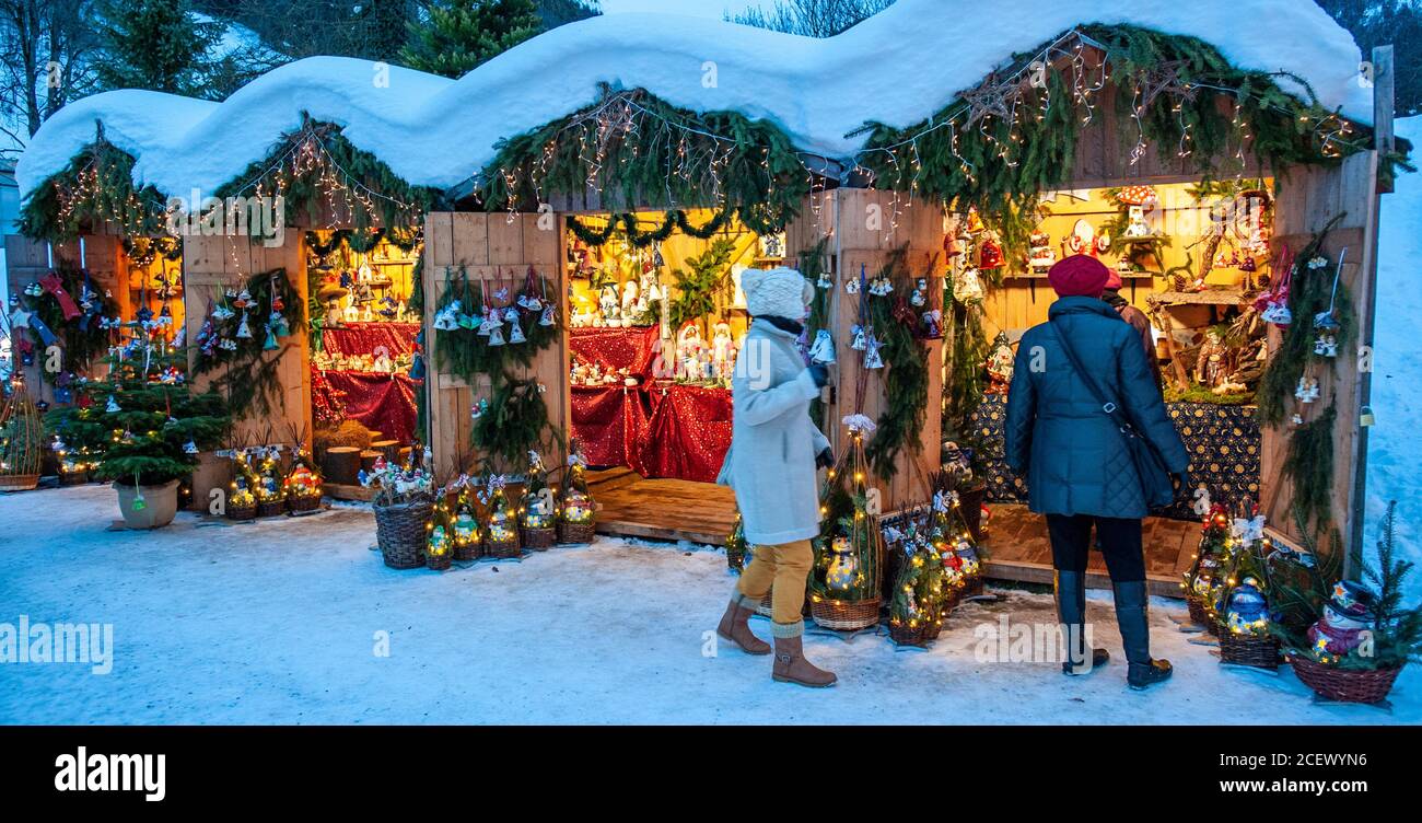 Ettal, Deutschland/Bayern – 31. Dezember 2019: Verschneite Weihnachtsmärkte mit beleuchteten Geschäften in Holzhütten mit Geschenken und handgefertigter Dekoration. Stockfoto