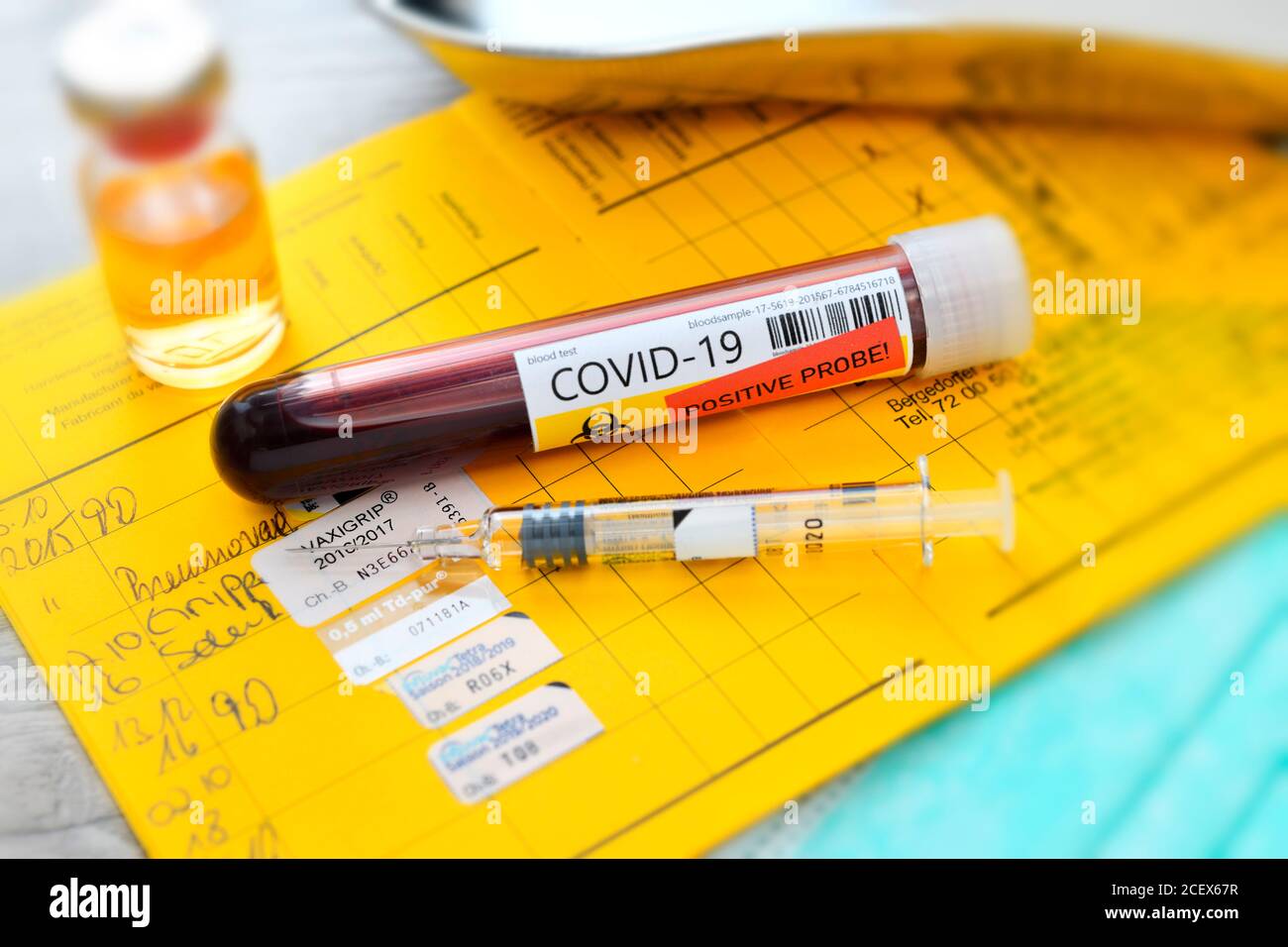 COVID-19 Blutentnahmeröhrchen und Spritze auf Impfkarte, Corona-Impfung Stockfoto
