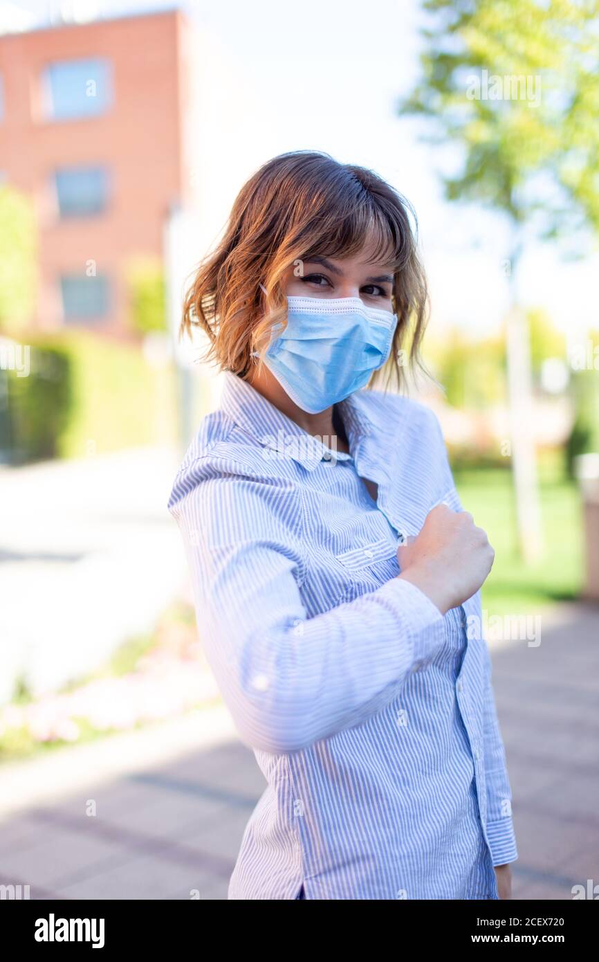 Frau in Maske Gruß mit Ellbogen im Freien im Park während Pandemie Stockfoto