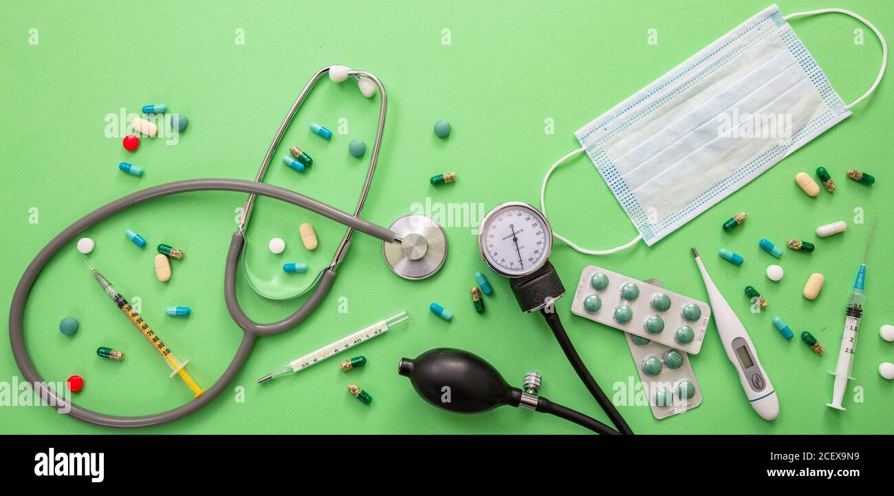 Blutdruckmessgerät, Medizin und Schutzmaske auf grünem Hintergrund. Coronavirus Schutz und Behandlung Konzept. Stockfoto