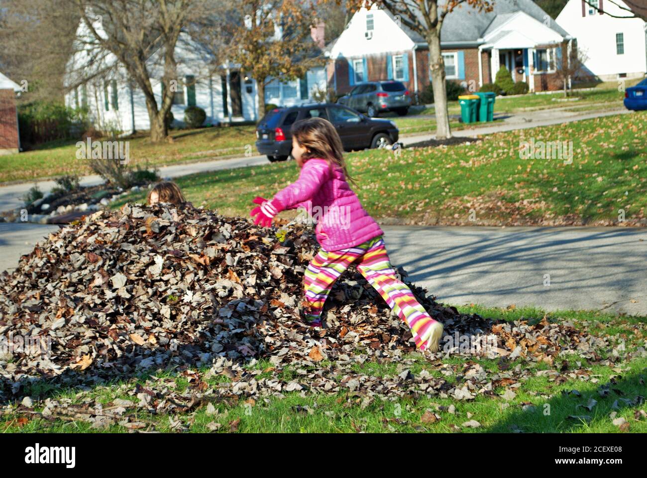 Junges Mädchen spielt in einem Stapel von Blättern Stockfoto