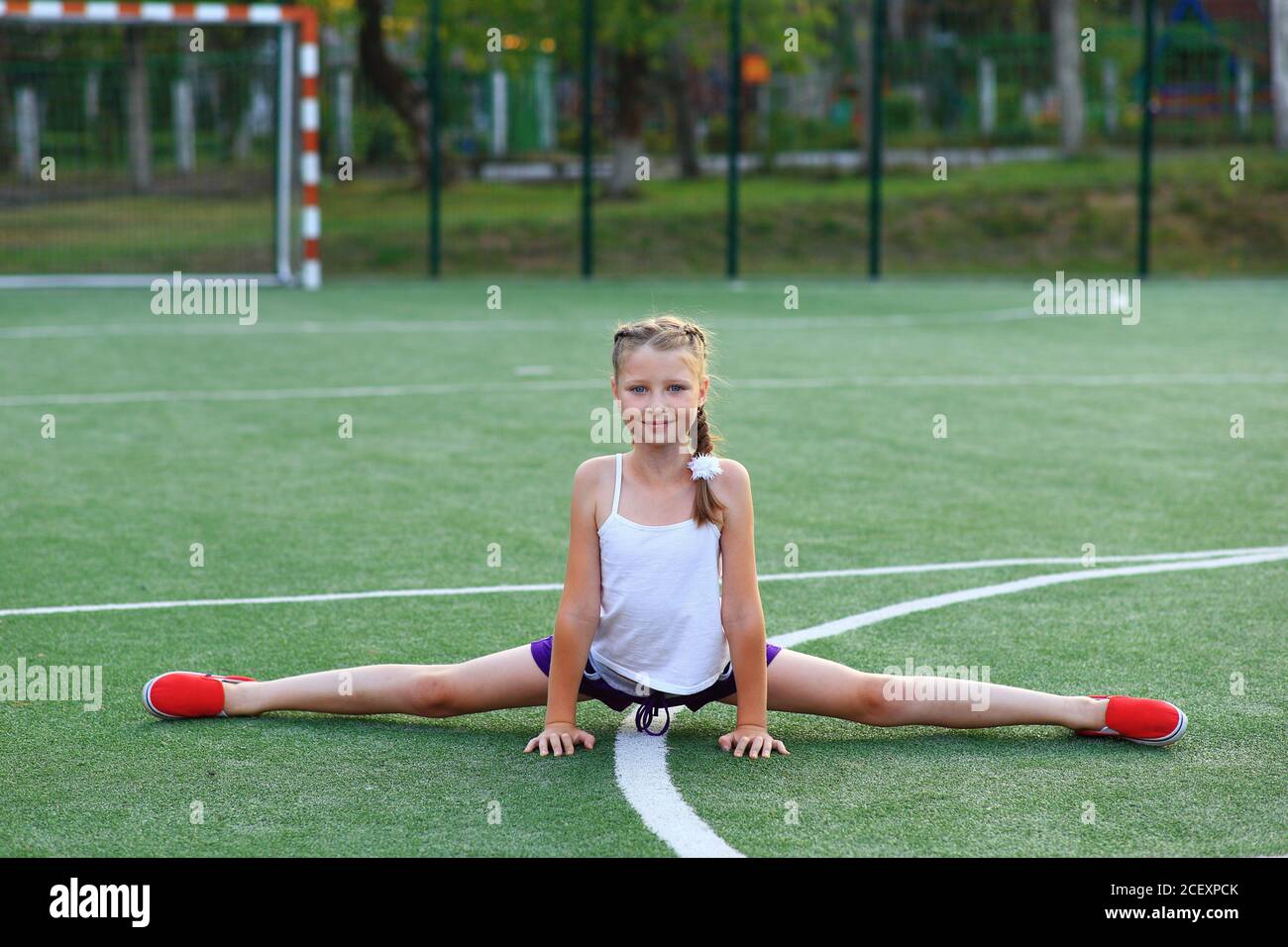 Das Mädchen sitzt auf dem Garn auf dem Sportplatz Stockfoto