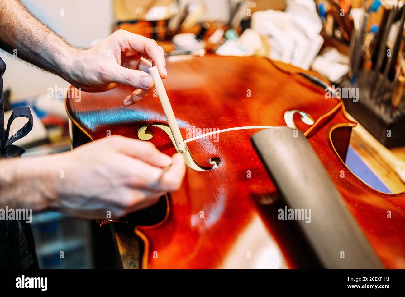 Crop anonyme Handwerker Einstellung Sound Post beim Bau Saiteninstrument In der Werkstatt Stockfoto