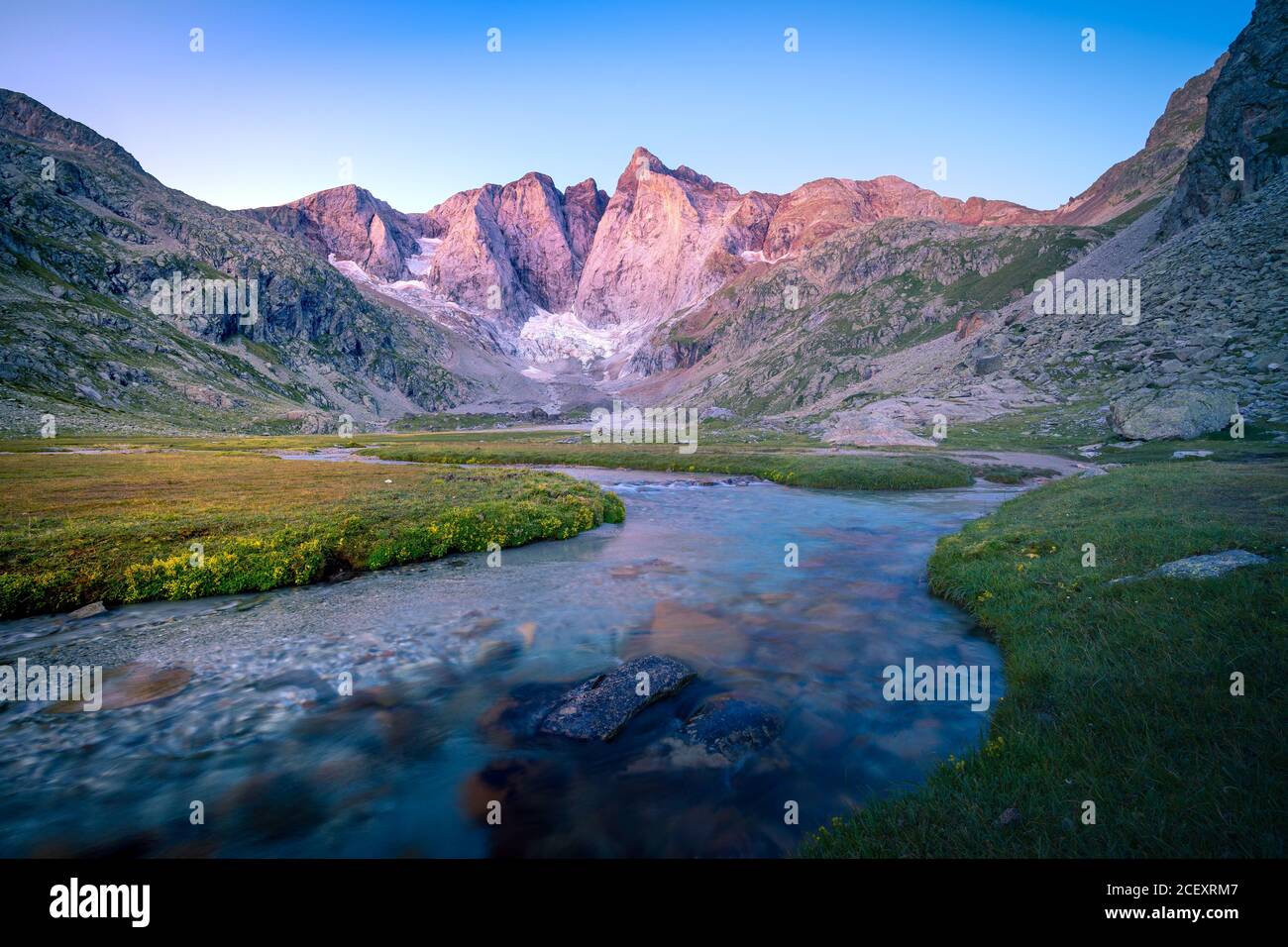 Spektakuläre Landschaft von grünen grasbewachsenen Tal mit Kurve Fluss umgeben Durch felsige Berge gegen wolkenlosen blauen Himmel am Sommertag Stockfoto
