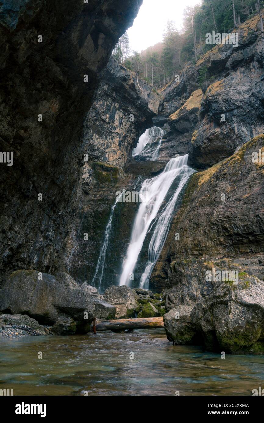 Kleine Wasserfall-Kaskade, die auf steile Felswand von rauher fließt Enge Schlucht mit Steinen bedeckt mit Moos in bergigen Gelände Stockfoto