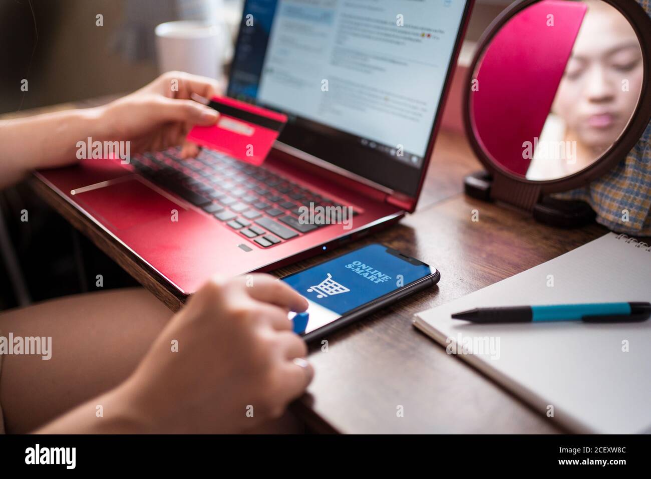 Frau sitzt am Tisch zu Hause und die Zahlung für Online-Einkäufe für Lebensmittel über die mobile App Stockfoto