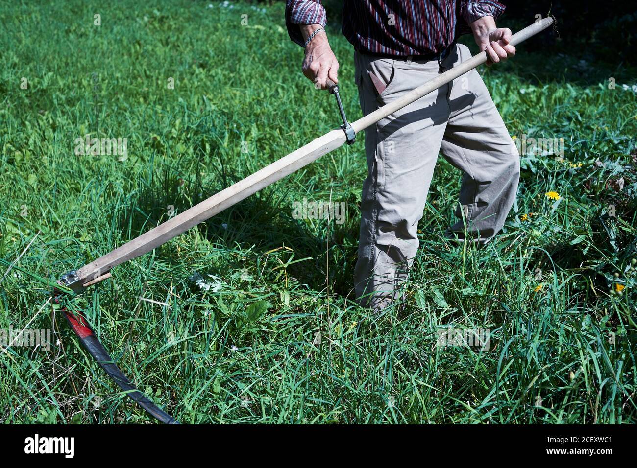 Der Mann, der Gras mit einer Sense schneidet. Hintergrund, Nahaufnahme. Stockfoto