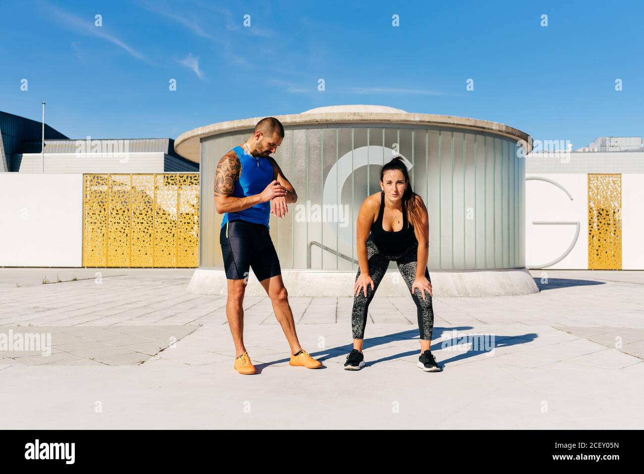 Ganzer Körper der bestimmt fit weiblich warten auf Signal während Männlicher Partner notiert Zeit mit Fitness-Tracker während Outdoor-Training Gemeinsam Stockfoto