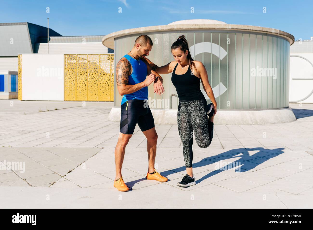 Ganzer Körper der bestimmt fit weiblich warten auf Signal während Männlicher Partner notiert Zeit mit Fitness-Tracker während Outdoor-Training Gemeinsam Stockfoto