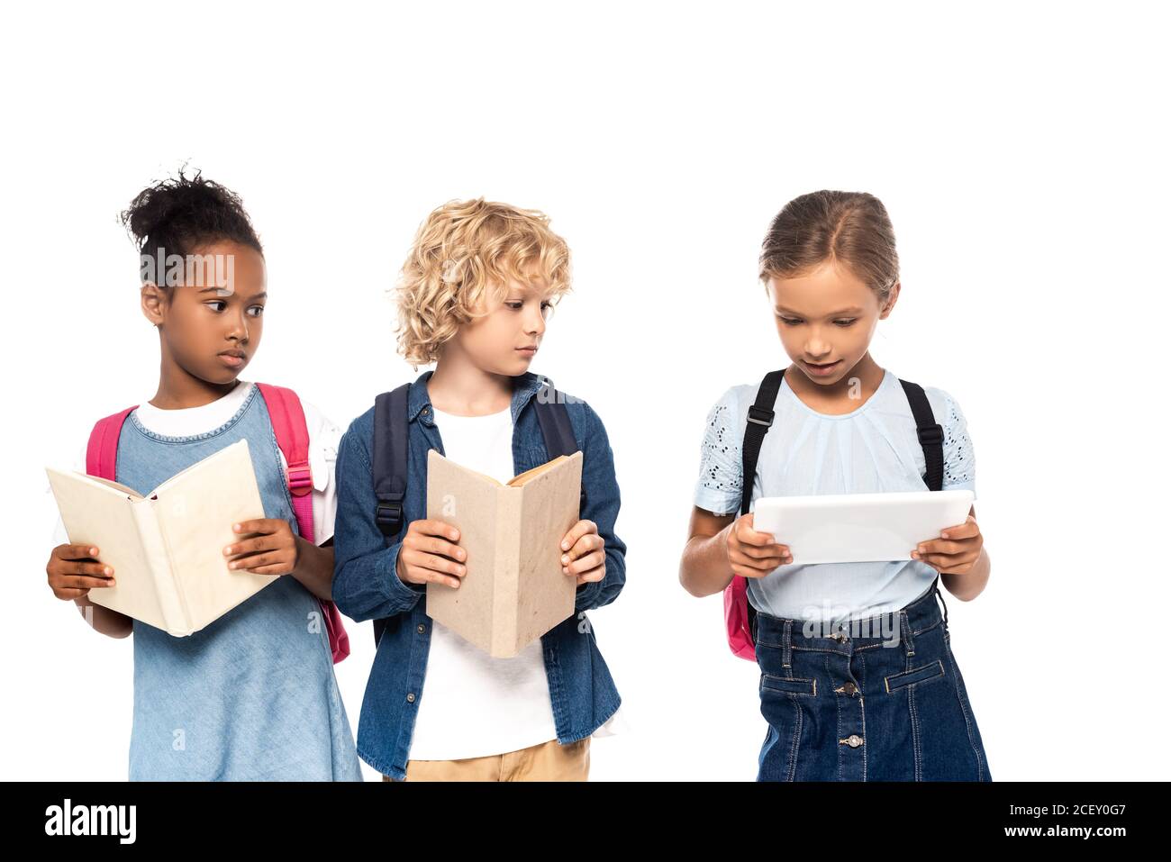 afroamerikanische Schulmädchen und lockig Schuljunge mit Büchern suchen Digitales Tablet in Händen von classmate isoliert auf weiß Stockfoto
