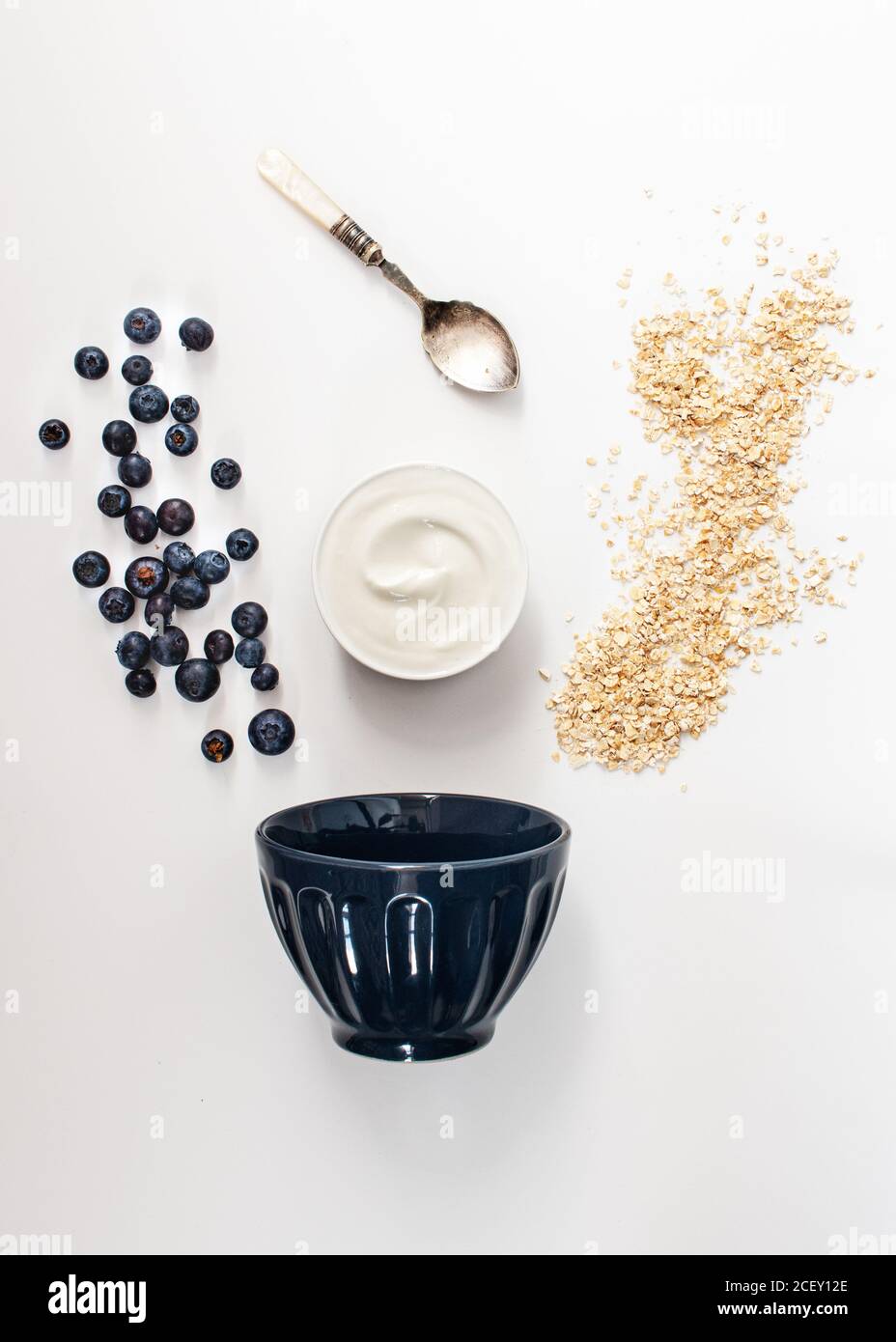 Aus den oben genannten Zutaten Hafer, frischer Joghurt und Heidelbeeren gesundes Frühstück auf weißem Tisch zu machen Stockfoto