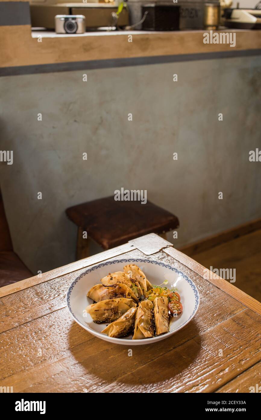 Teller mit traditionellen asiatischen Gyozas gefüllt mit Gemüse und serviert Mit Sriracha heiße Sauce mit Senf und Soja auf Holz Tabelle Stockfoto