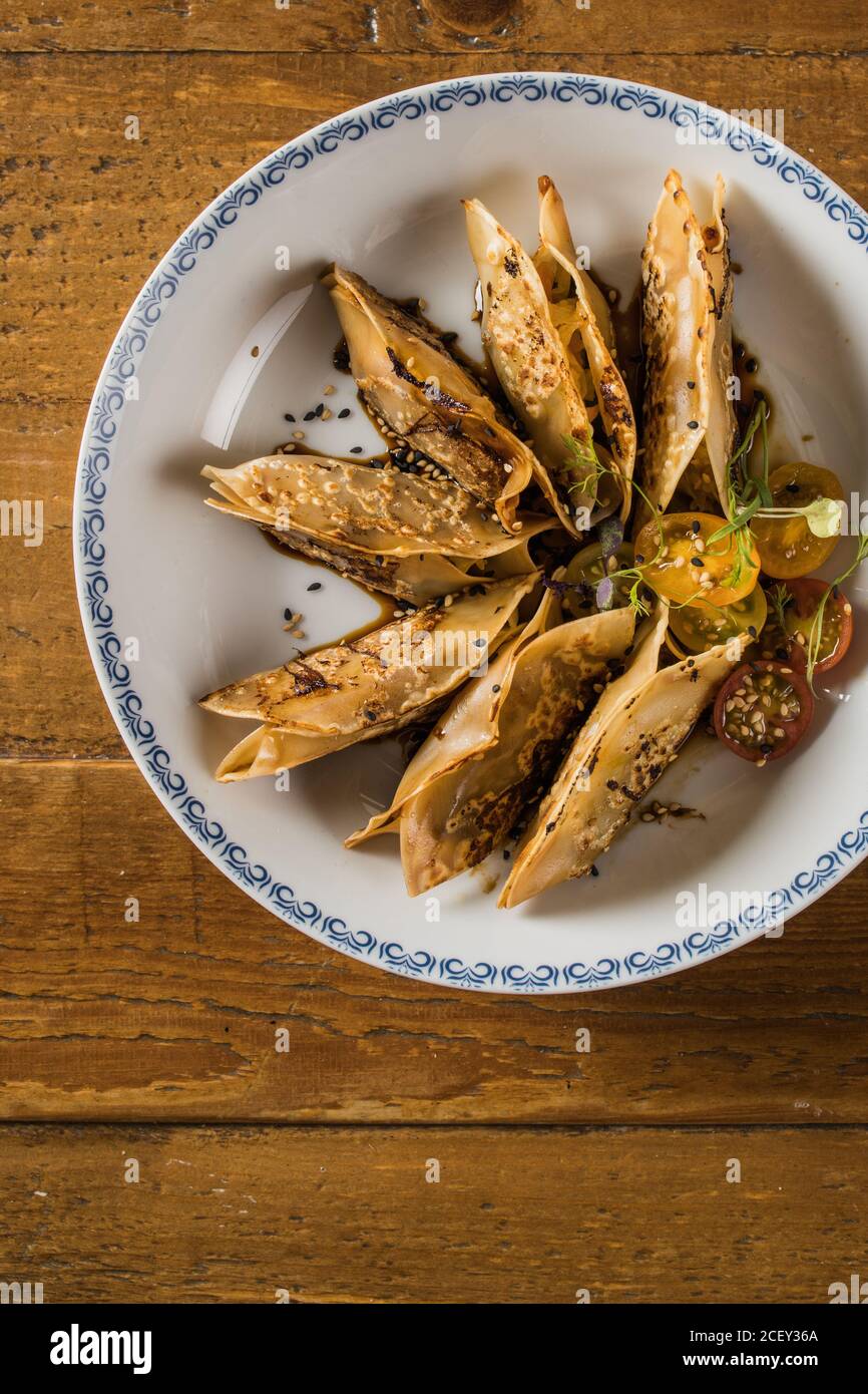 Teller mit traditionellen asiatischen Gyozas gefüllt mit Gemüse und serviert Mit Sriracha heiße Sauce mit Senf und Soja auf Holz Tabelle Stockfoto