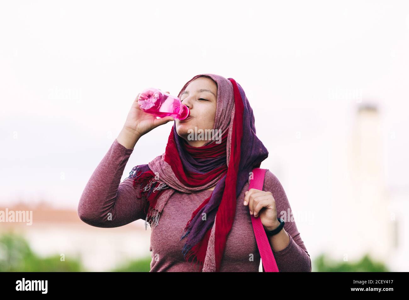 Arab weibliche Athletin in Hijab und aktive tragen stehen auf Straße und genießen Sie frisches Wasser nach dem Training Stockfoto