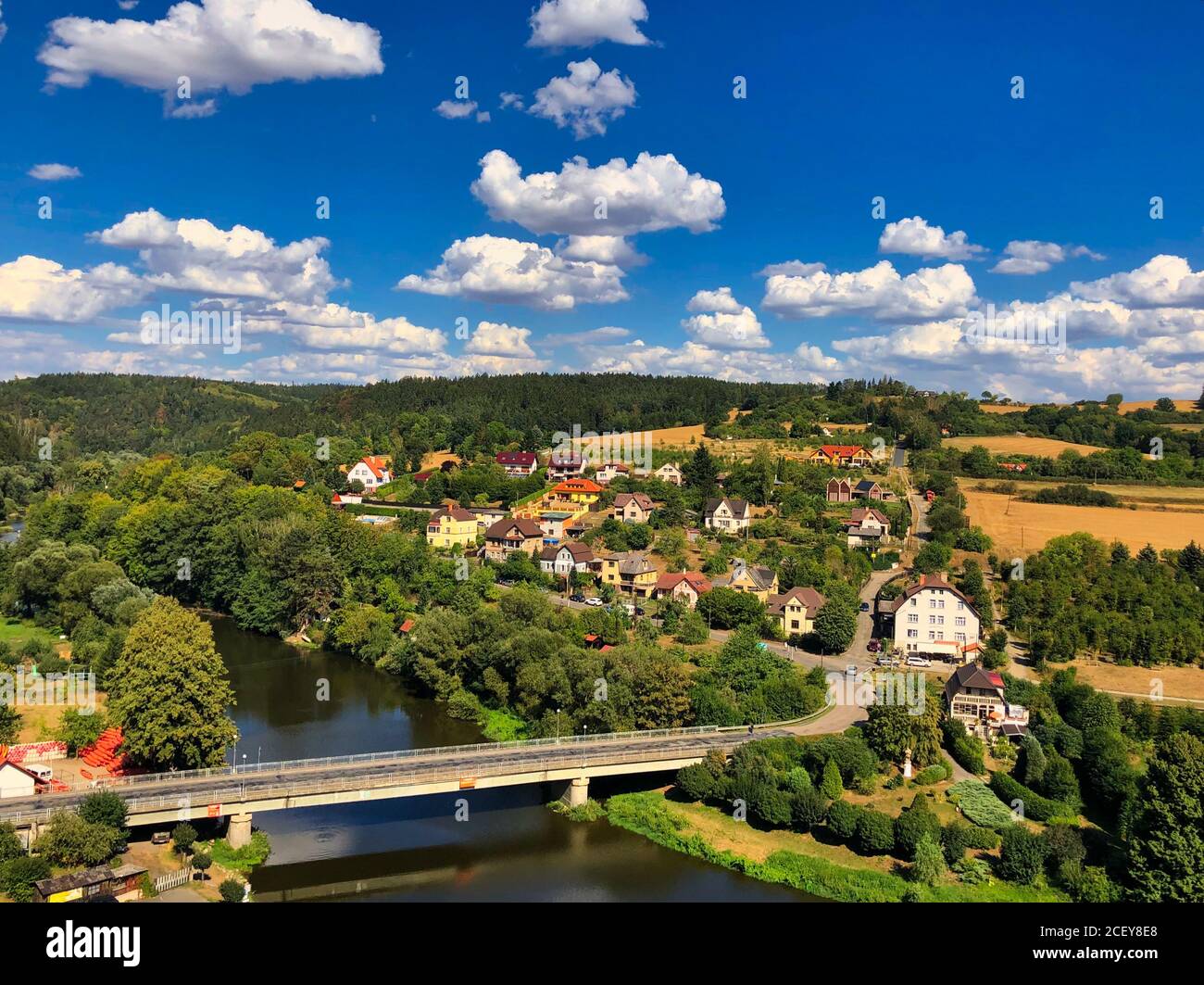 Eine farbenfrohe Fotoansicht eines Dorfes mit einigen Wolken am blauen Himmel, Sazava Fluss und Brücke von einem Cesky Sternberk Schloss in Tschechien aufgenommen Stockfoto