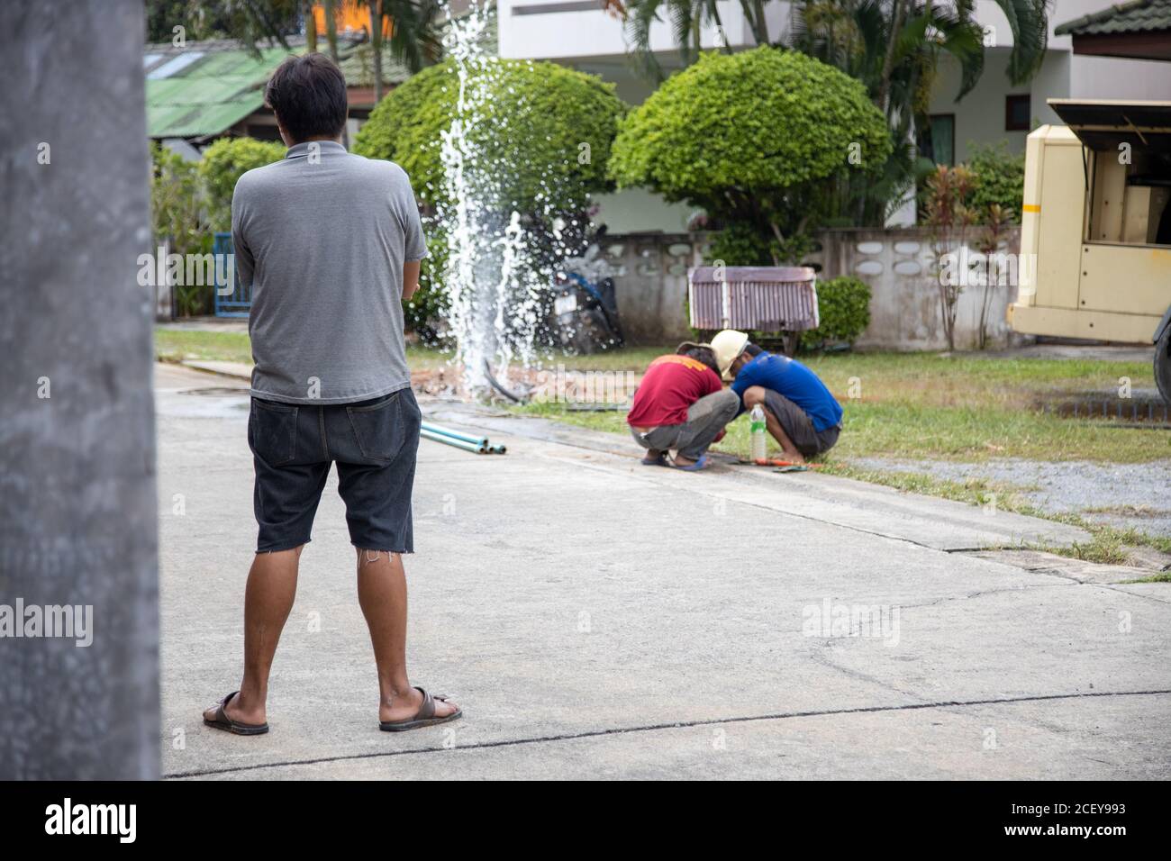 Bruch der Wasserleitung. Wasser fließt in einen Brunnen. Versorgungsarbeiter hält Schraubenschlüssel und in Graben reparieren die gebrochene Pip. Stockfoto
