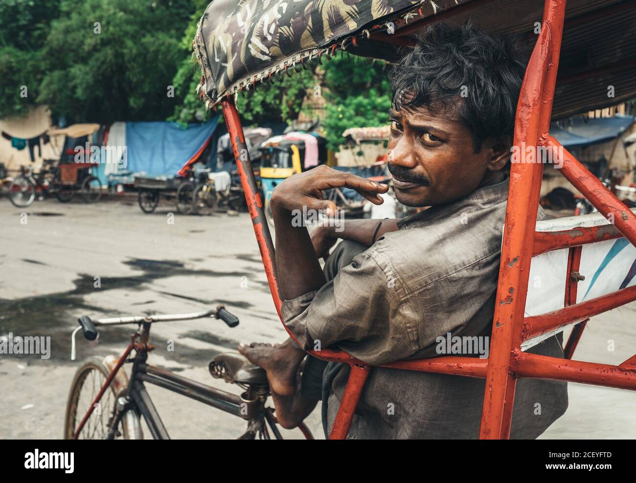 Neu Delhi, Indien - 14. August 2016: Armer Rickshaw-Arbeiter wartet auf Kunden auf der Straße in Neu Delhi, Indien Stockfoto