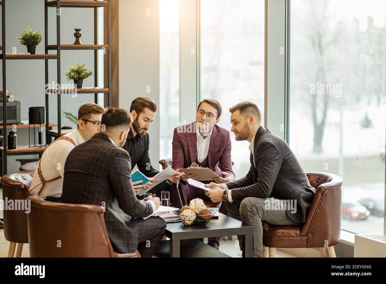 Junge Führungskräfte des Unternehmens Coworking im Büro, in formeller Kleidung gekleidet, halten Aufzeichnungen und entwickeln weitere Aktionsplan Stockfoto