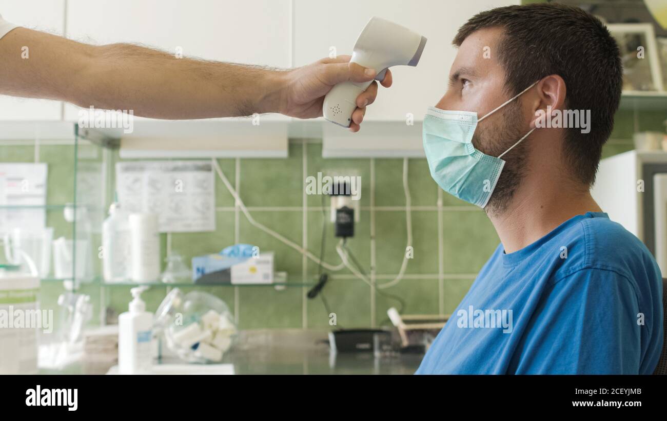 Messung der Temperatur für Coronavirus-Infektion mit Gesichtsmaske. Stockfoto