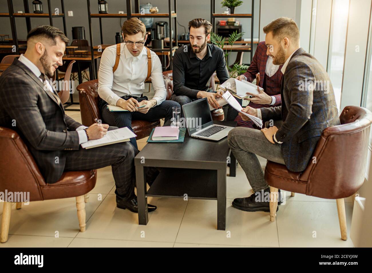 Junge Führungskräfte des Unternehmens Coworking im Büro, in formeller Kleidung gekleidet, halten Aufzeichnungen und entwickeln weitere Aktionsplan Stockfoto