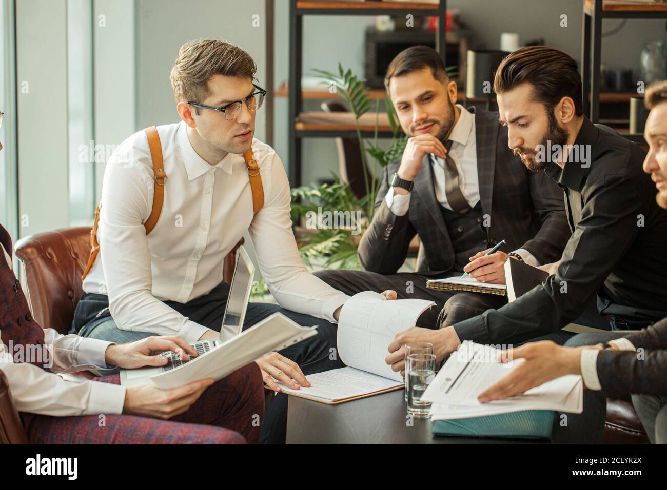 Junge kaukasische Geschäftspartner teilen und kommentieren Berichte. Halten Papiere und Notizbücher, Notizen machen und Aufzeichnungen über ihren Markt, in Form Stockfoto