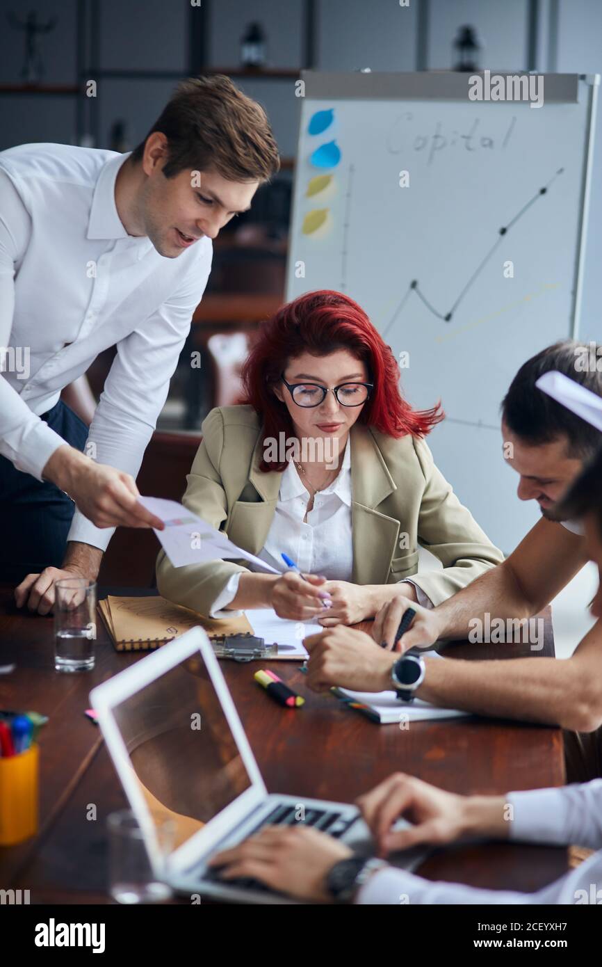 Moderne Führerin des kreativen Teams, Unternehmen sitzen mit Geschäftspartnern und hören Sie ihnen zu. Verwenden von Bleistiften, Papieren und Laptops zum Arbeiten. Flipchart Stockfoto